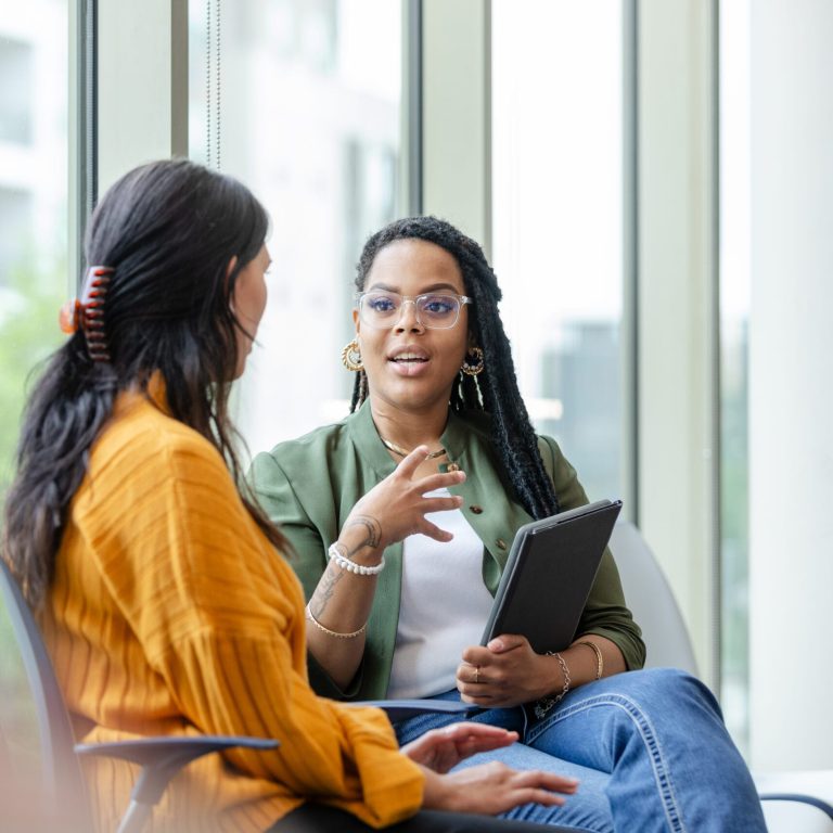 A female therapy patient listens attentively to a female therapist discuss coping strategies.